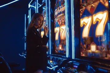 A woman smiling by bright slot machines showing lucky symbols, showcasing the exciting slot offerings at JL56.
